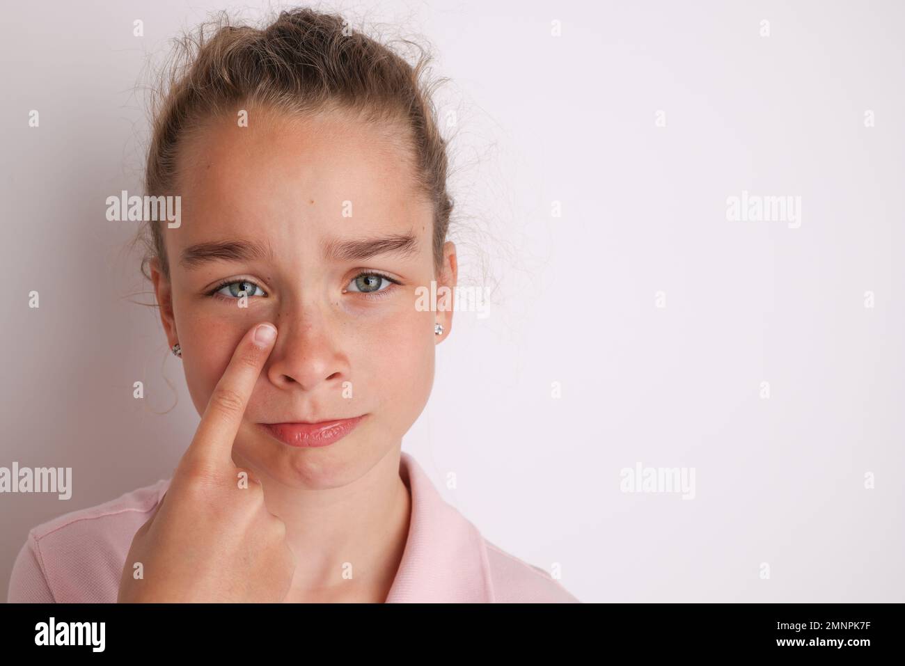 Little emotional teen girl in pink shirt 11, 12 years old on an isolated white background