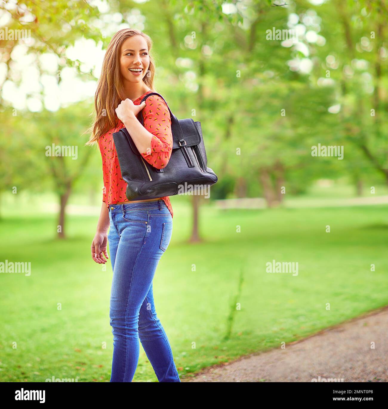 On a leisurely stroll through the park. a young woman walking in a park. Stock Photo