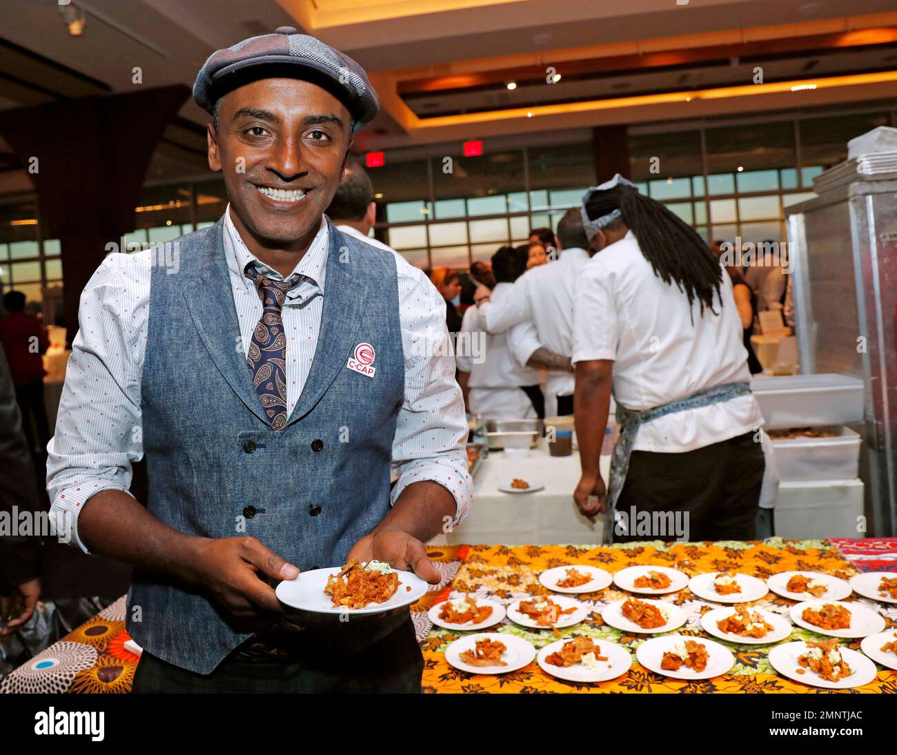 Chef Marcus Samuelsson, who is Ethiopian, but was raised in Sweden, founder of Red Rooster Harlem and more than a dozen other restaurants, holds a tasting plate of Dorowat "lasagna," with injera (Ethiopian flatbread), ayib (Ethiopian cheese), rosemary, and crispy skin, during the C-CAP (Careers through Culinary Arts Program) annual benefit, Tuesday, Feb. 27, 2018, in New York. (AP Photo/Kathy Willens) Stock Photo