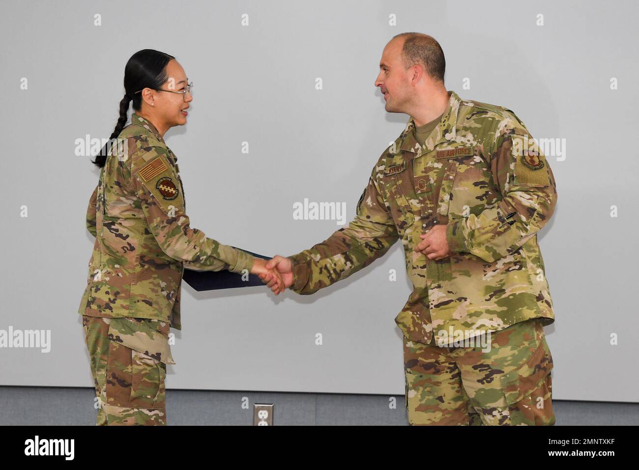 Master Sgt. Michael Kennedy, Hanscom career assistance advisor, congratulates Senior Airman Ling Yu, 66th Comptroller Squadron financial analyst, after presenting her with a certificate of achievement at Hanscom Air Force Base, Mass., Oct 6 for completing courses at Hanscom University that earned her Wingman Level.  To achieve Wingman level, Yu completed four core, one intermediate, and one advanced class in addition to her course project. Stock Photo