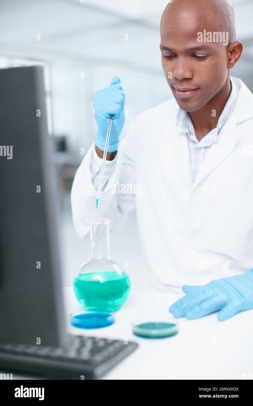 Combining technology and chemistry. An attractive male scientist adding