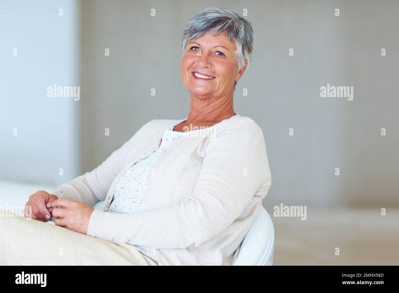 Mature woman relaxing on chair. Portrait of smiling mature woman while ...