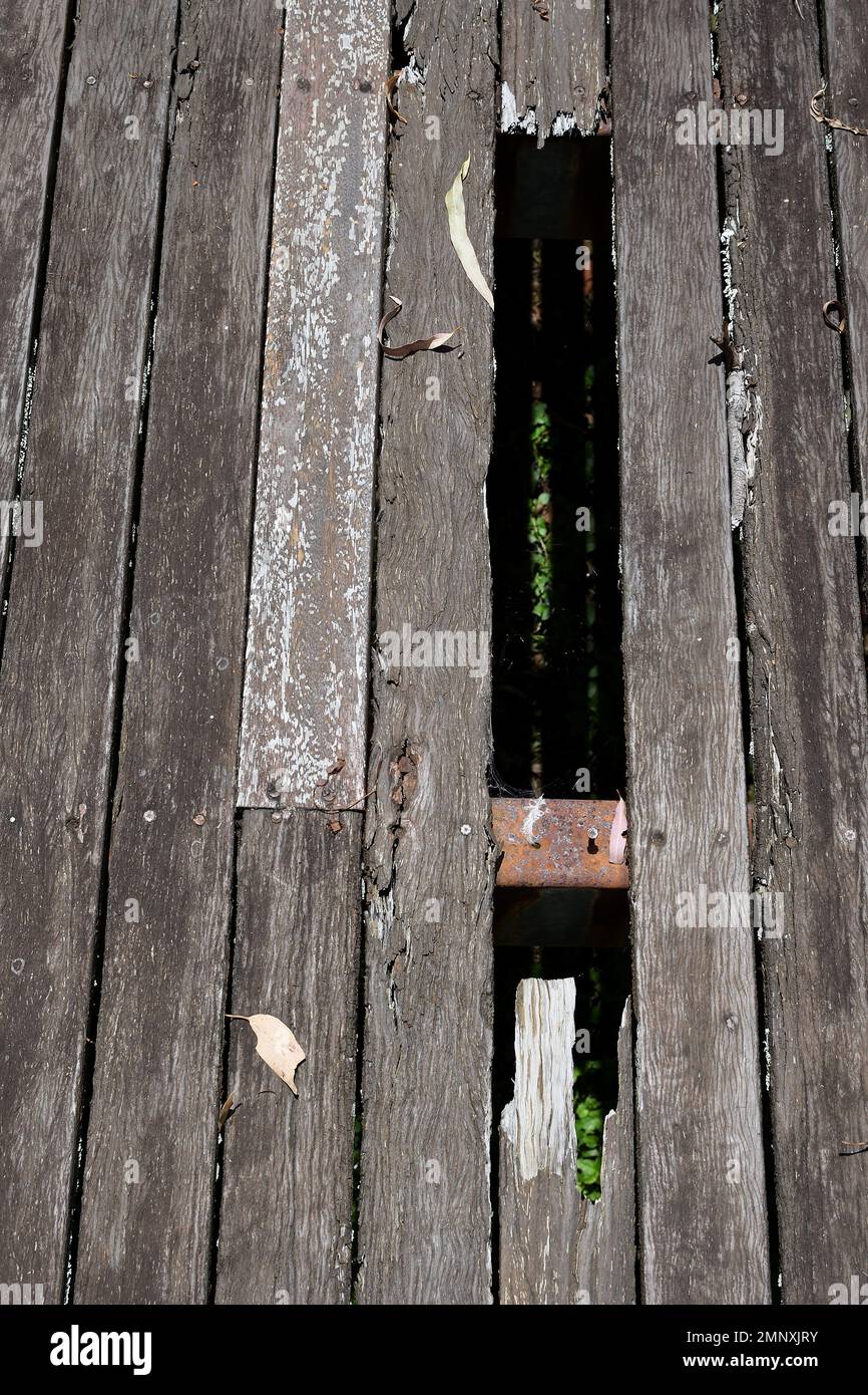 Dangerous, rotted, unvarnished, wooden decking floorboards with holes