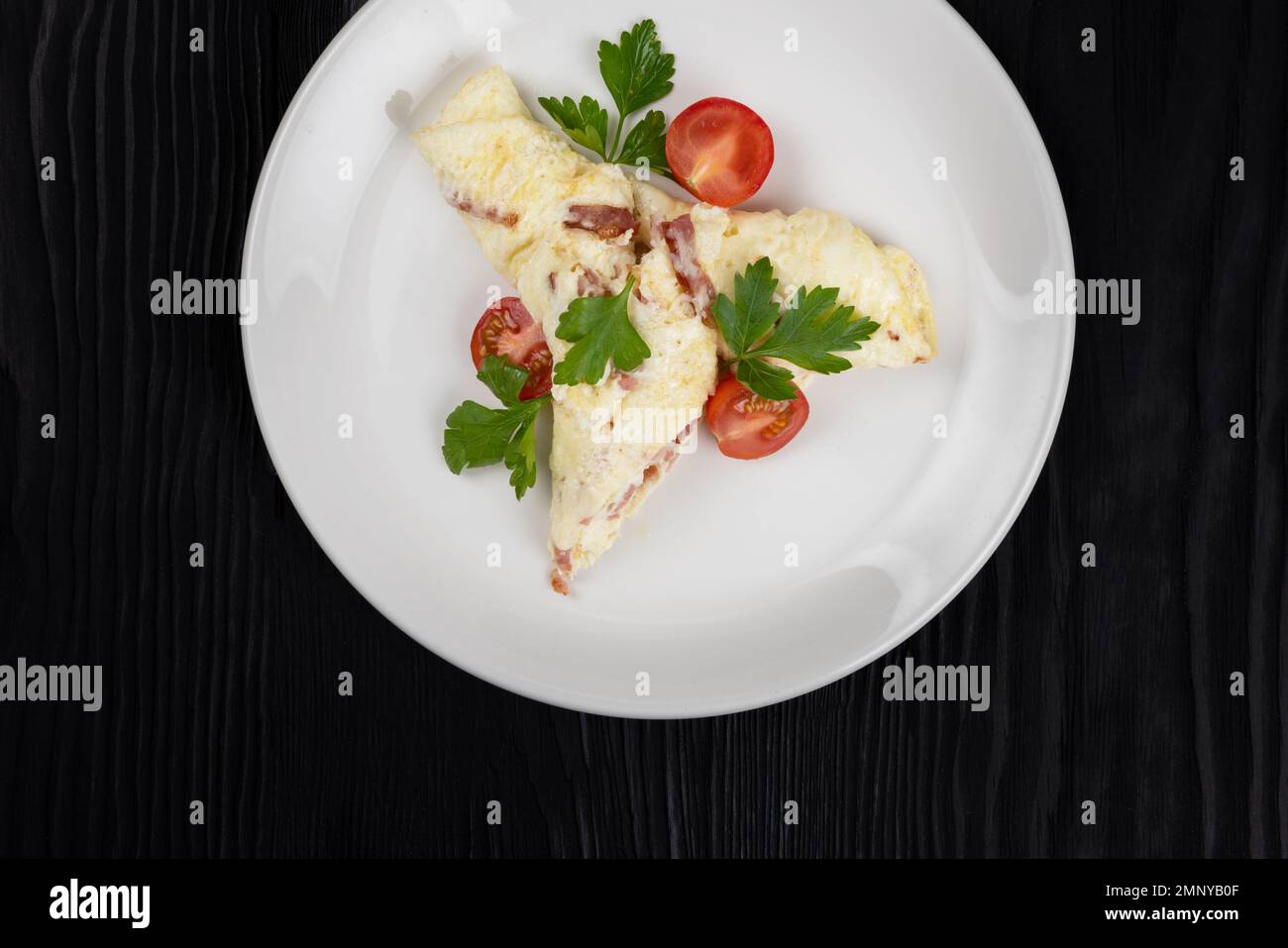 Omelet with Ham and Cheese on black wooden background Stock Photo