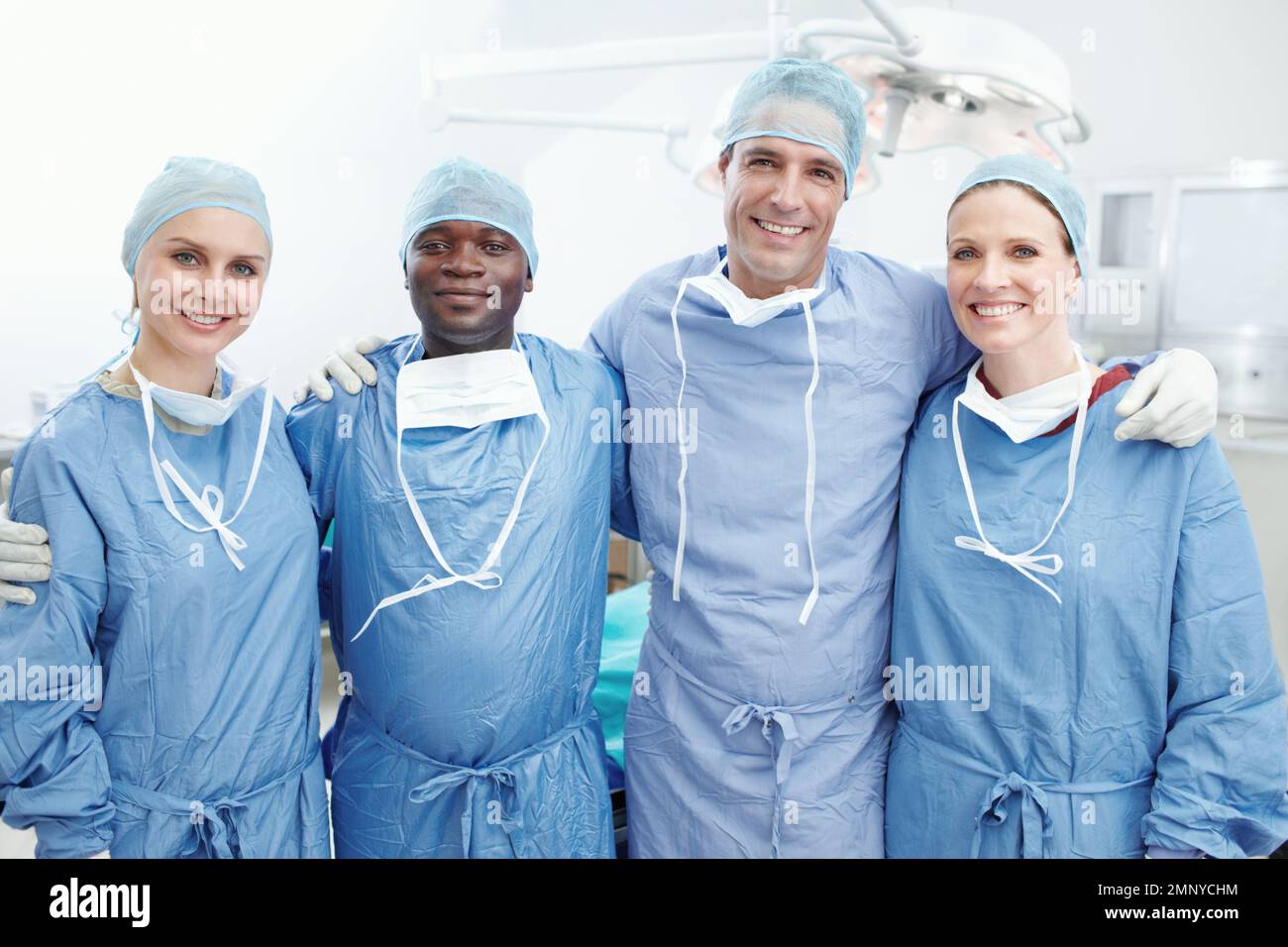 We are part of a family in this hospital. A happy team of medical surgeons and doctors embarcing one another in an operating theatre - Teamwork. Stock Photo