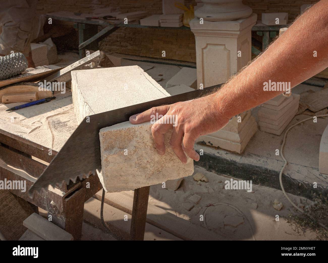 The sculptor's hands, which process a block of white stone on the