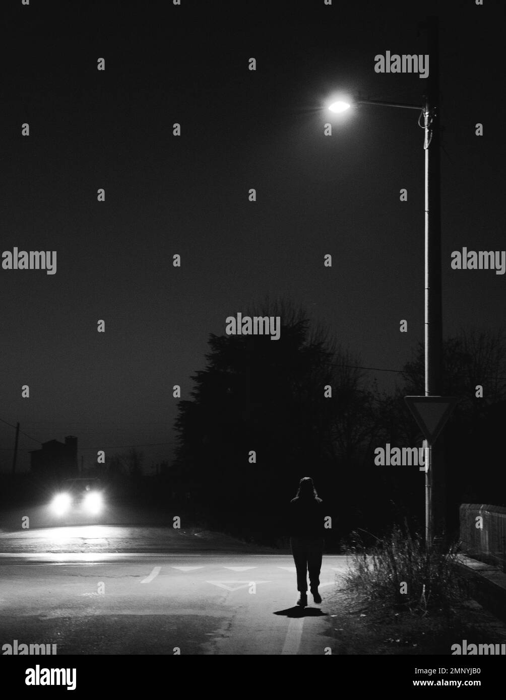 Woman walks through the country roads at night Stock Photo