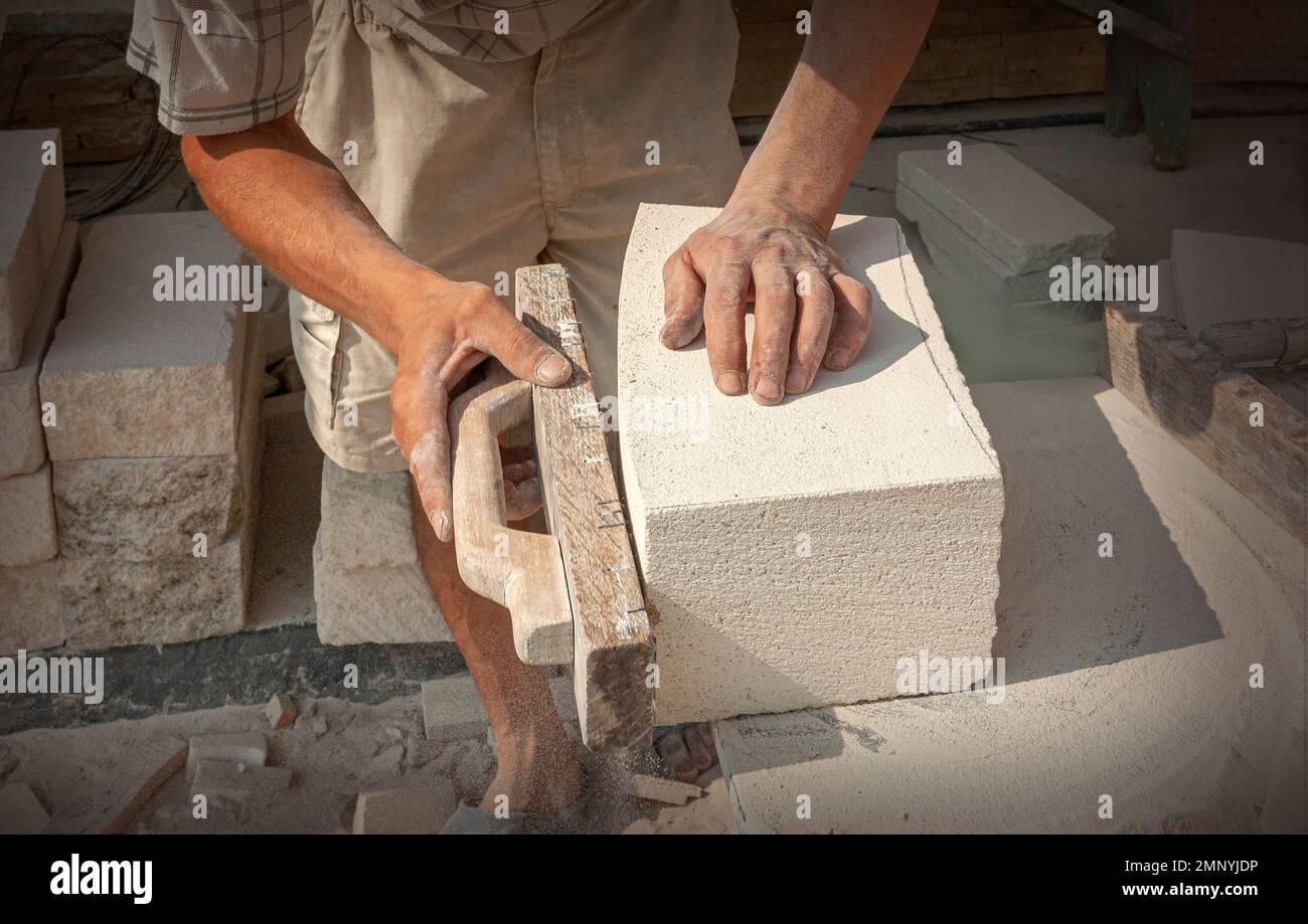 The sculptor's hands, which process a block of white stone on the