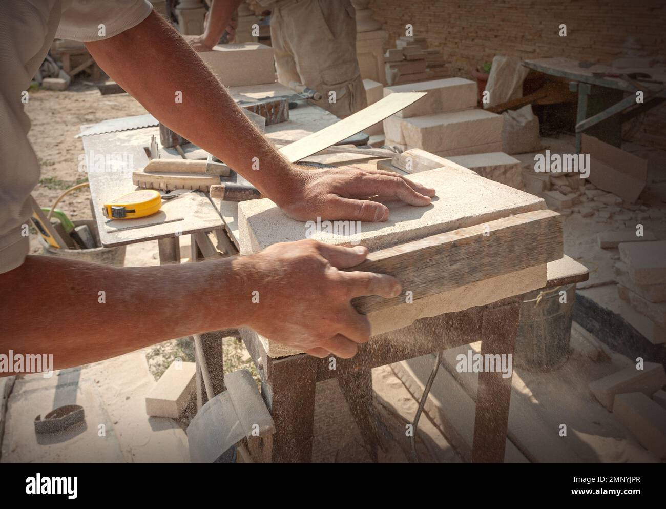 The sculptor's hands, which process a block of white stone on the