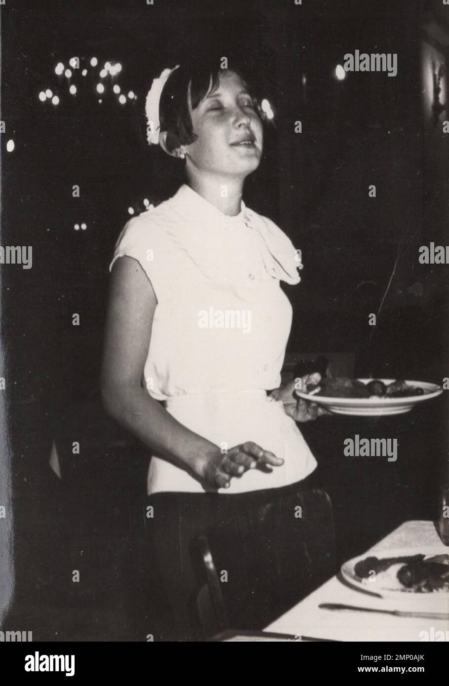 vintage moment / vintage funny moment / vintage photograph / power of the moment / magic moments / vintage eating / eating / feeling the flow or a simple waitress who is enjoying her job. Possibly it is a busy day in the restaurant at the 1950s. Stock Photo