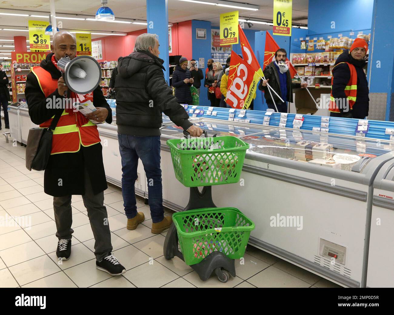 A man pulls his trolley as employees of French retail giant Carrefour Group  demonstrate against job cuts with union flags inside a Carrefour store, in  Marseille, southern France, Friday, Feb. 9, 2018.