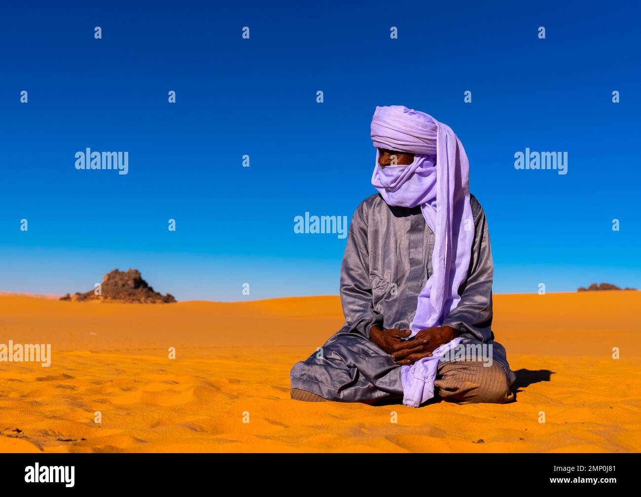 Tuareg sit in the Sahara desert, North Africa, Erg Admer, Algeria Stock Photo