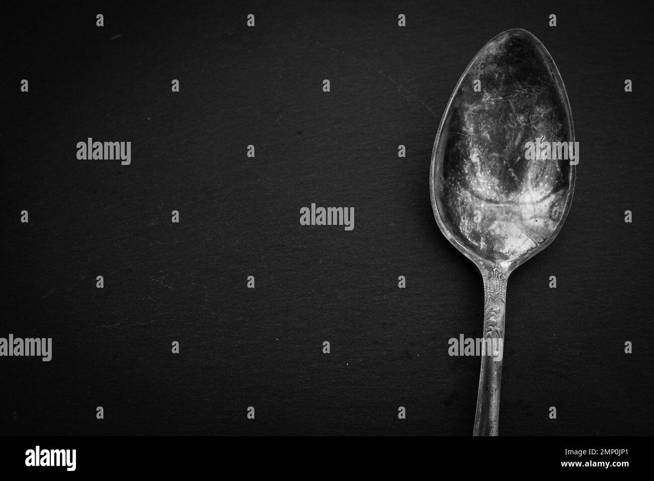 Antique cutlery on black background. Silver spoon isolated, black and white. Silverware with copy space. Silver cutlery. Stylish retro utensil. Stock Photo