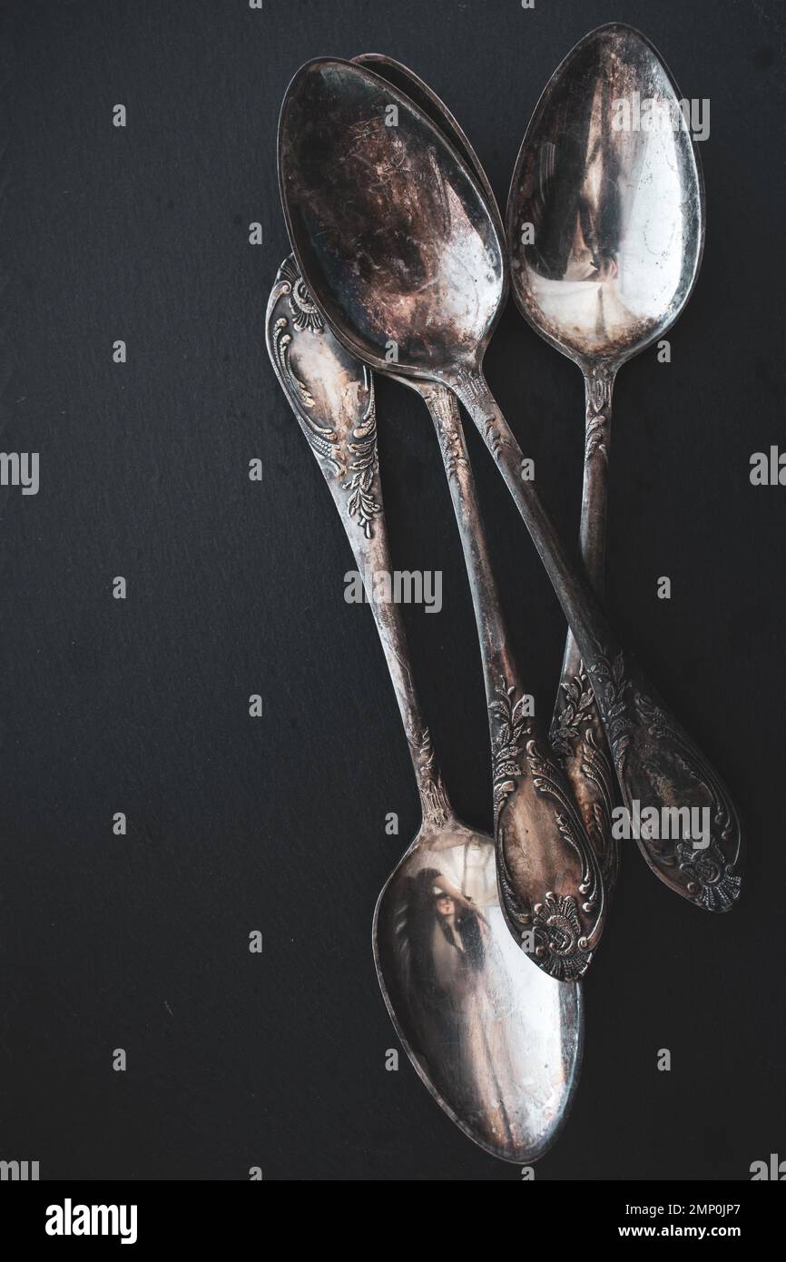 Antique cutlery on black background. Silver spoons isolated. Silverware with copy space. Silver cutlery. Stylish retro utensil. Vintage kitchen tools. Stock Photo