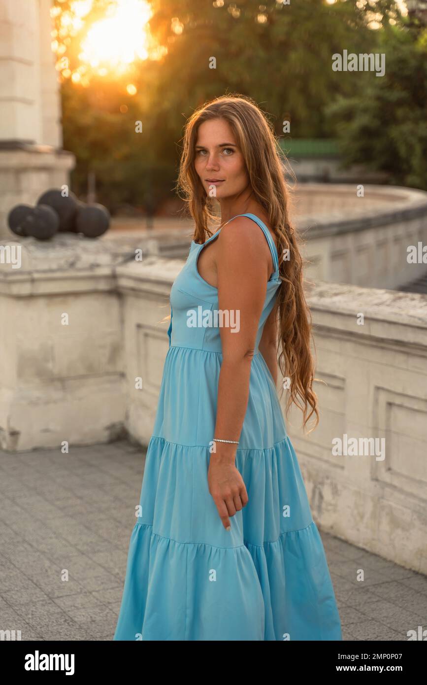 Woman sunset blue dress. Portrait of a woman with long hair and a blue ...