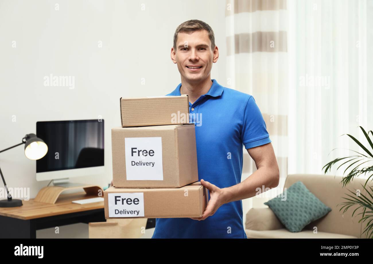 Courier holding parcels with stickers Free Delivery indoors Stock Photo ...