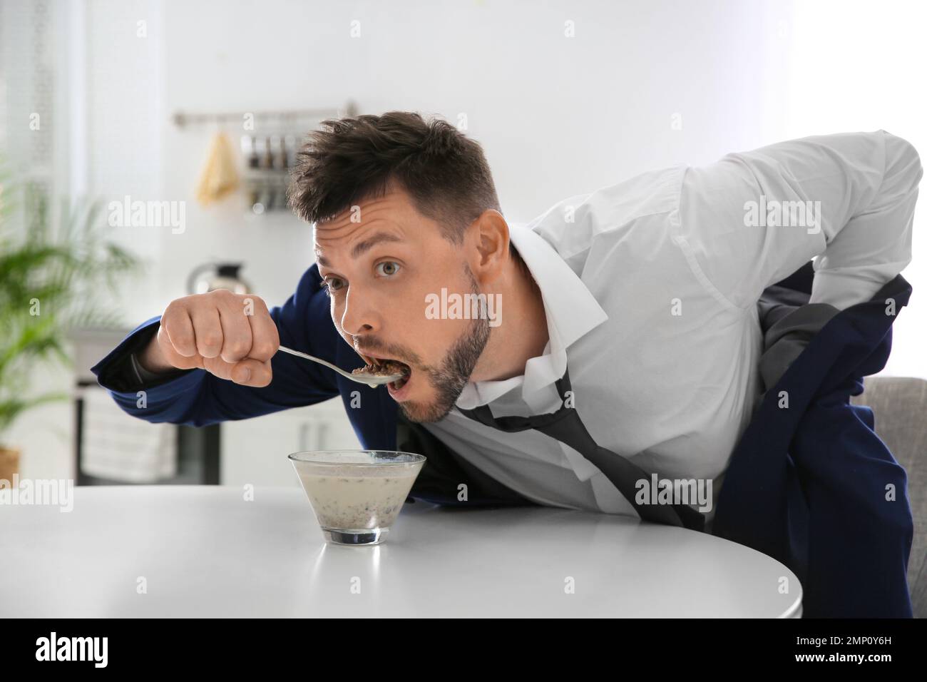 Man eating breakfast in hurry at home. Morning preparations Stock Photo