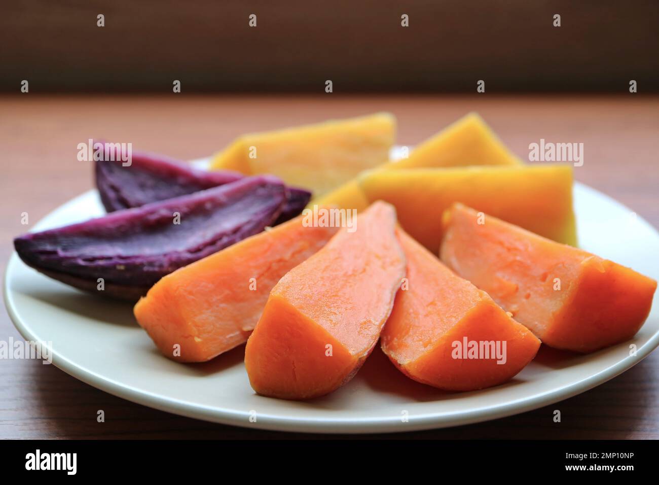 Plate of three different color steamed sweet potatoes, a good source of healthy carbs Stock Photo