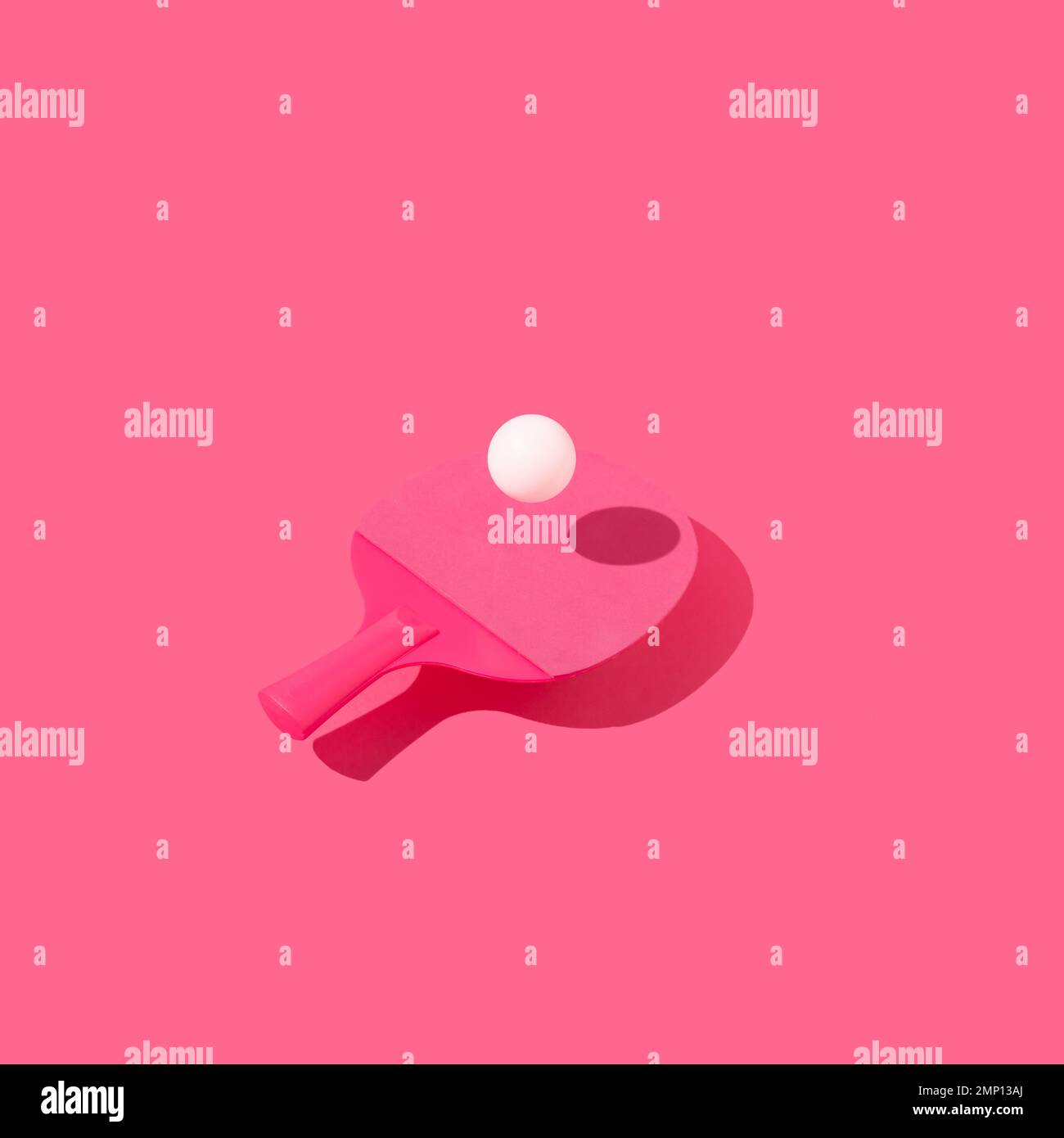 Table tennis racket and ping pong ball levitating above pink background