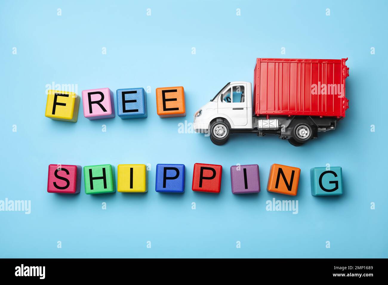 Toy truck with words FREE DELIVERY on blue background, flat lay. Logistics and wholesale concept Stock Photo