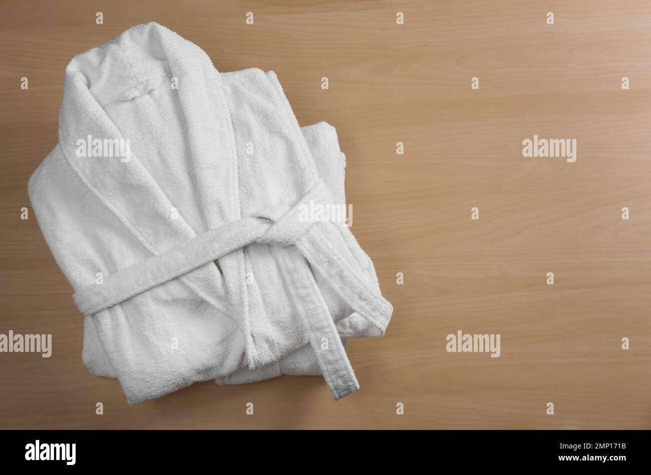 Clean folded bathrobes on wooden background, top view. Space for text