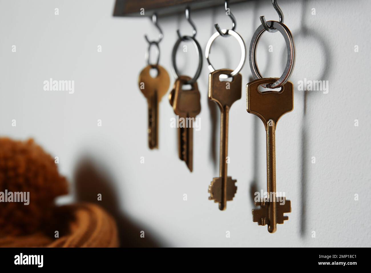 Holder with different keys on light grey wall indoors Stock Photo