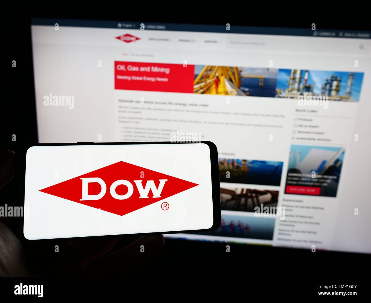 Person holding smartphone with logo of US chemical company Dow Inc. on screen in front of website. Focus on phone display. Stock Photo