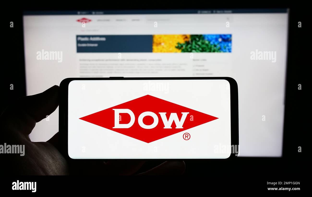Person holding cellphone with logo of US chemical company Dow Inc. on screen in front of business webpage. Focus on phone display. Stock Photo