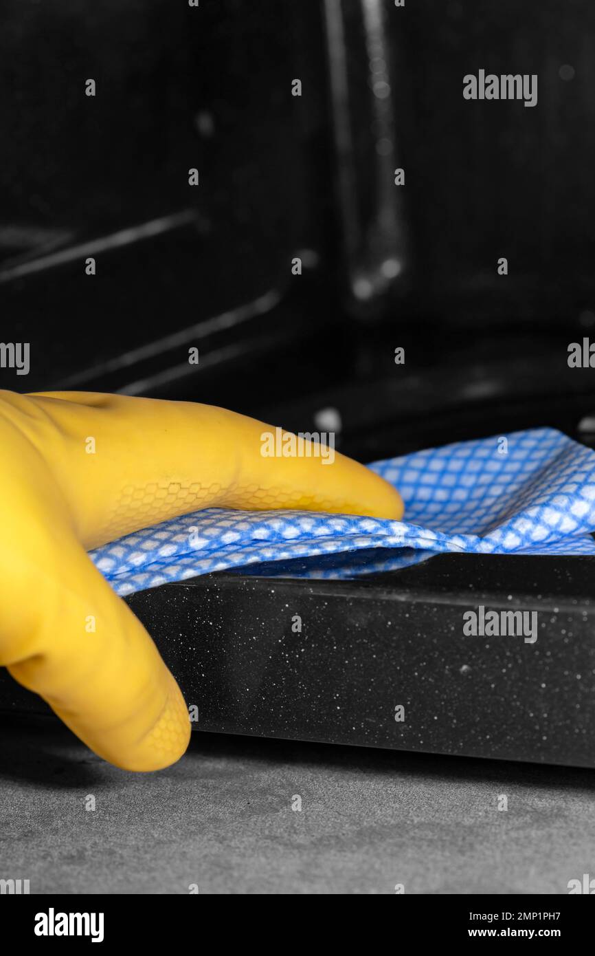 Person cleaning the inside of a microwave oven, wearing yellow rubber