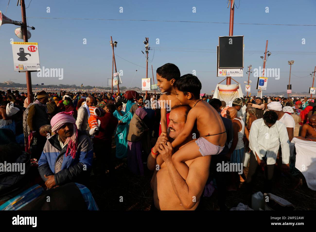 A Hindu devotee carries his children before taking a holy dip at the ...
