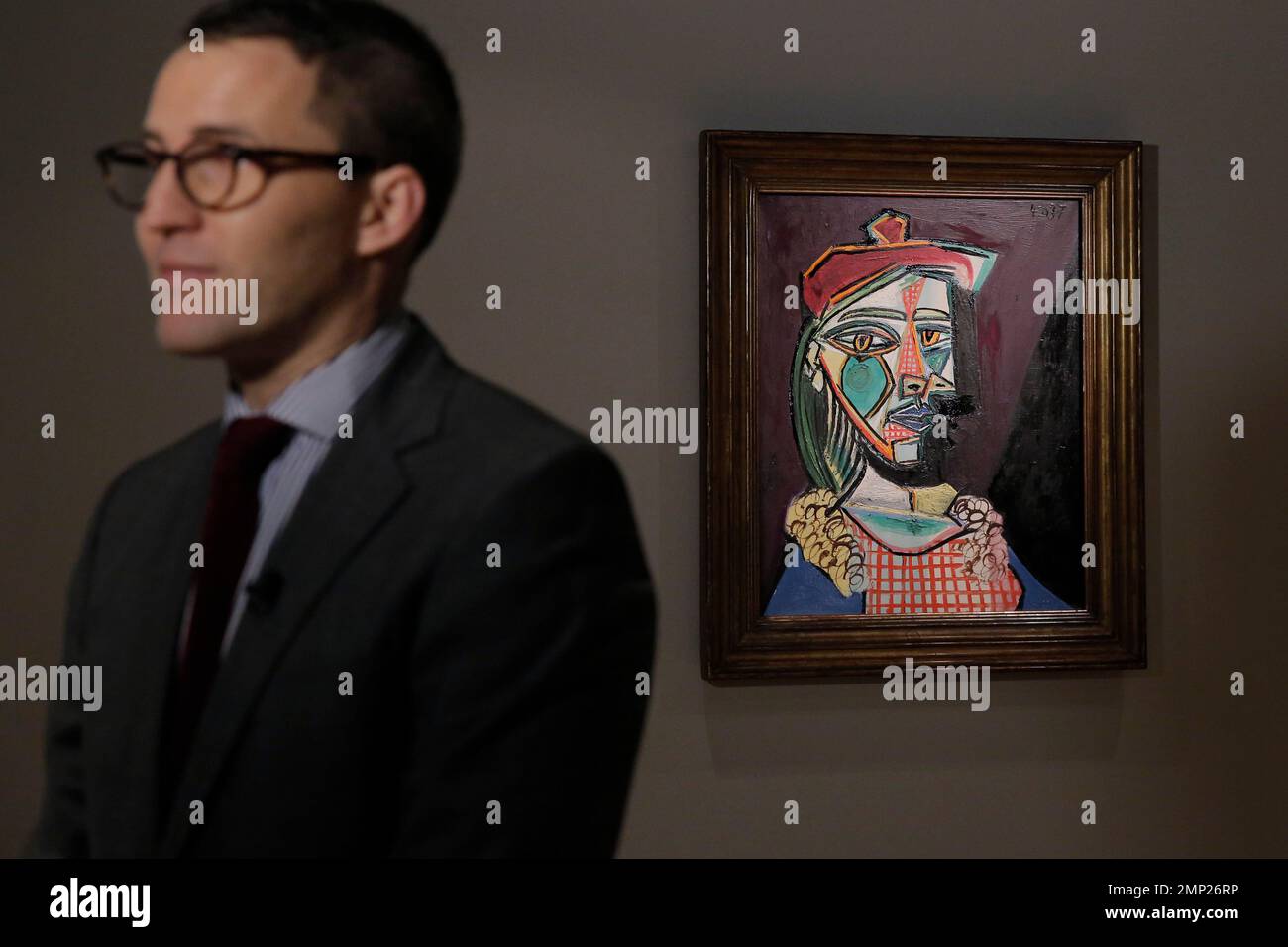 A staff member stands in front of a Pablo Picasso's painting "Woman in