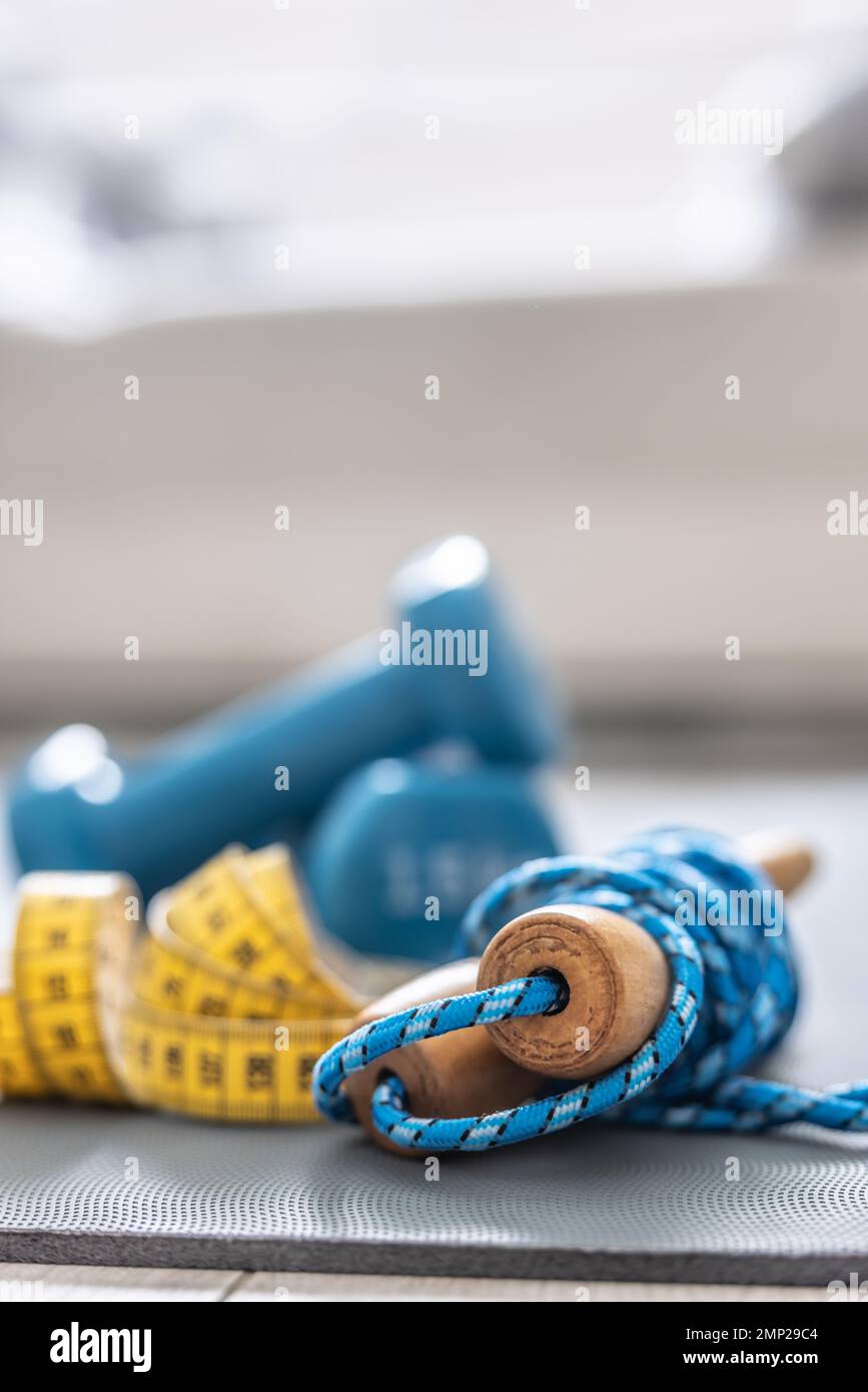 Jump rope, dumbbells and tape measure on the mat at home in the living ...