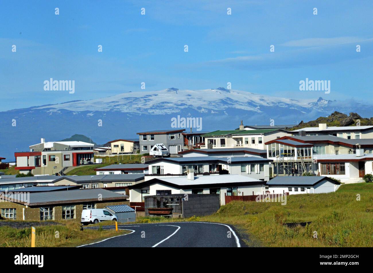 Iceland, Island of Heimaey:   modern houses in the upper town, with the snow-covered massif of Mýrdalsjökull on the mainland as a backcloth. Stock Photo