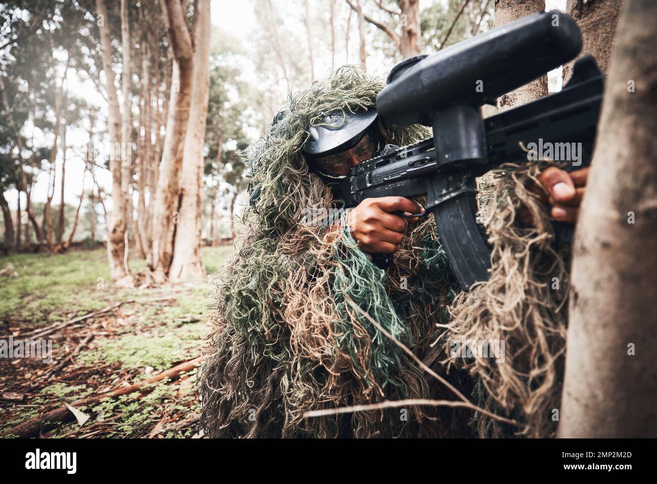 Paintball gun, forrest and man with aim by trees for outdoor war game