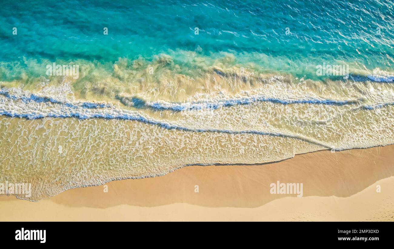 TOP VIEW. Relaxing aerial beach scene, summer vacation holiday template. Waves surf with amazing blue ocean lagoon, sea shore, coastline. Perfect aerial drone top view. Peaceful bright beach, seaside Stock Photo
