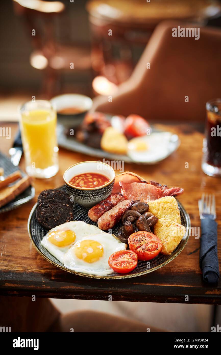 Breakfast fry up brunch gastro pub full english beans bap tomato black pudding potato hash brown scrambled egg bacon tasty food meal classic Stock Photo