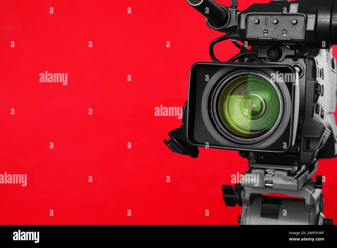 Modern professional video camera on red background, closeup. Space for ...