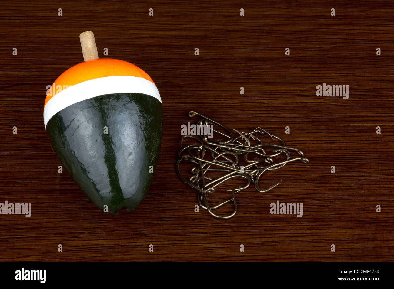 Fishing hooks and old angling float on a polished wooden surface Stock Photo
