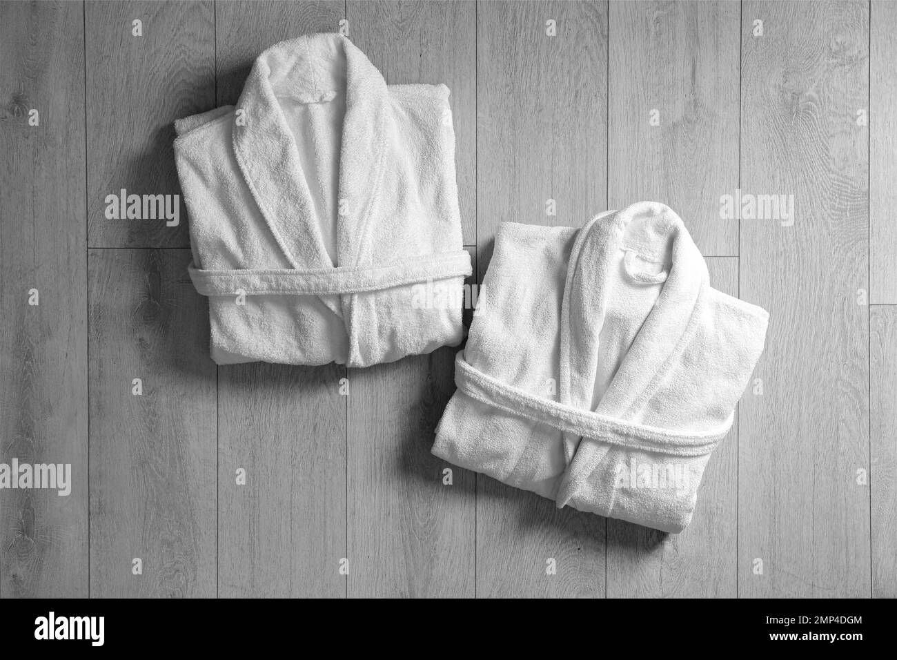Clean folded bathrobes on light wooden background, flat lay Stock Photo