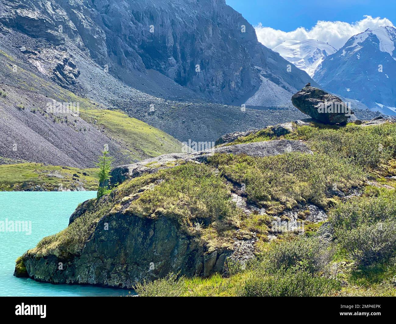 Mountain lake with turquoise water Karakabak in the Altai mountains with snowy peaks and glaciers with under the clouds and green grass with a hanging Stock Photo