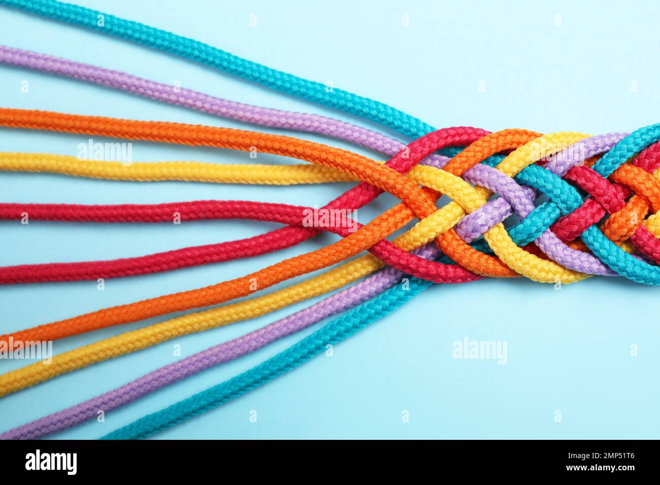 Braided colorful ropes on light blue background, top view. Unity ...