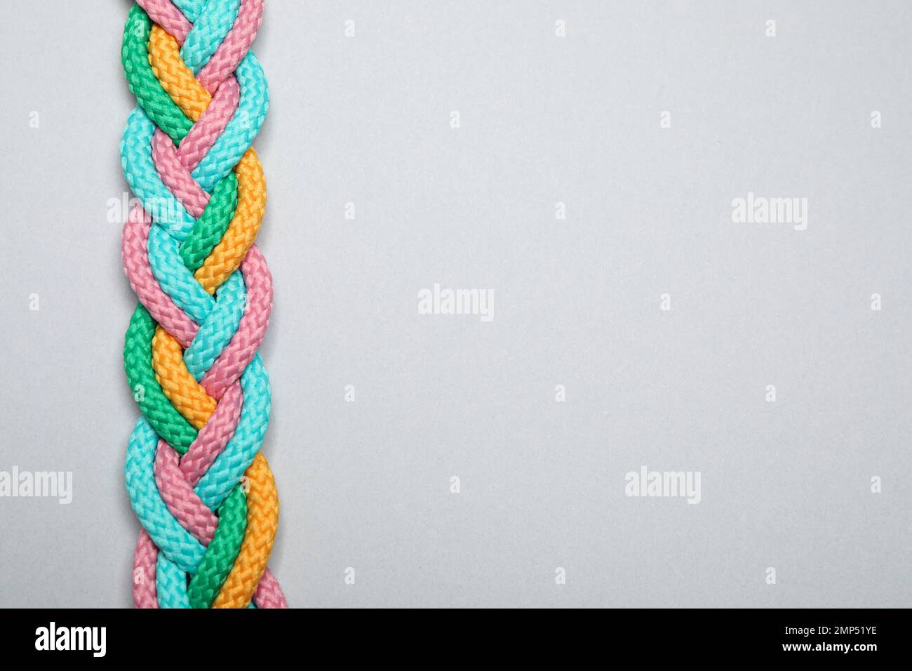 Top view of braided colorful ropes on light grey background, space for ...