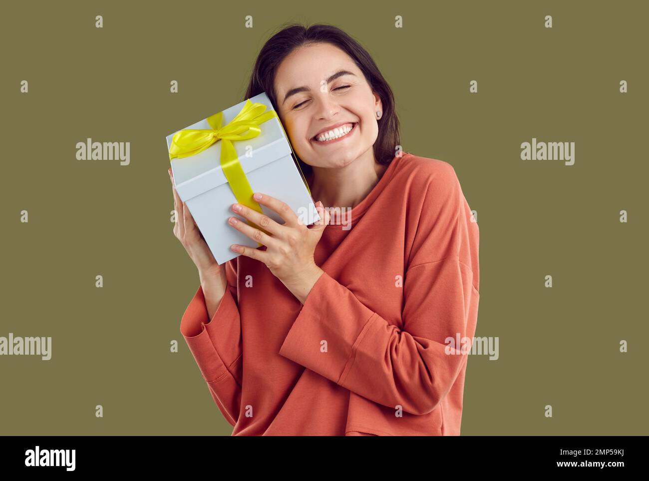 Smiling brunette woman in red sweatshirt is hugging a present with ...