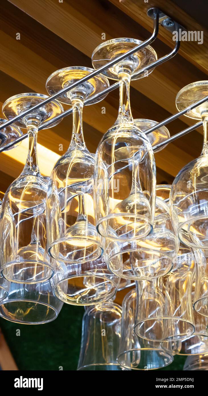clean wine glasses hang over the bar. Glass, utensils, objects. Stock Photo