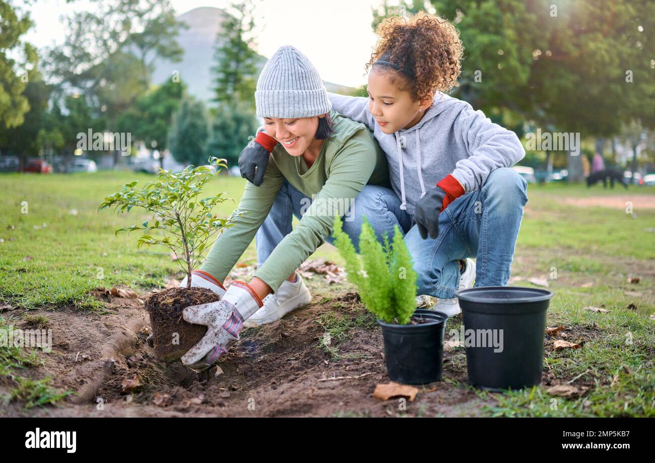 Woman, child and nature park with a plant for gardening trees or agriculture in garden. Happy volunteer family team helping and planting growth Stock Photo