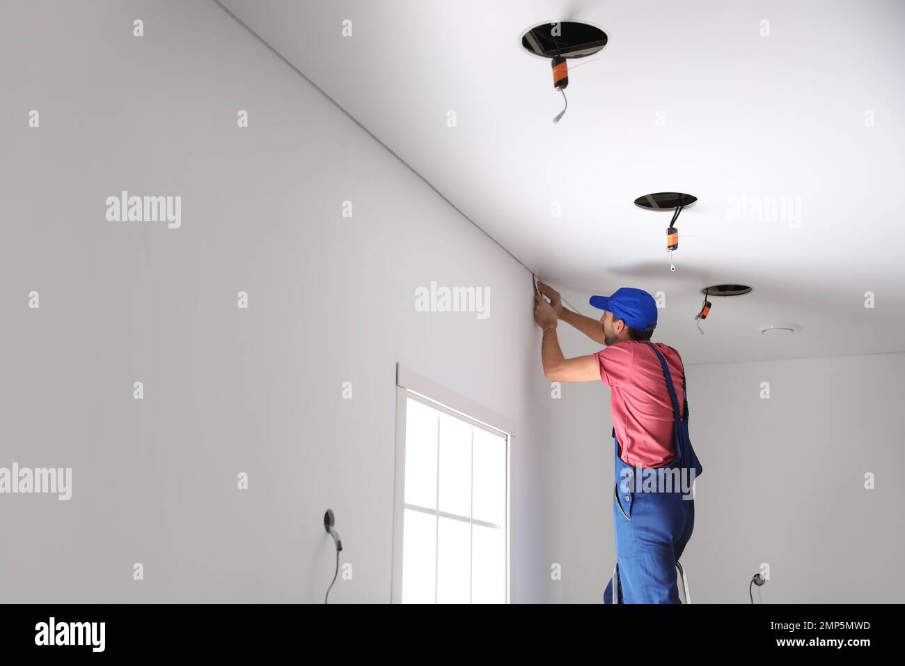 Worker installing stretch ceiling in empty room. Space for text Stock ...