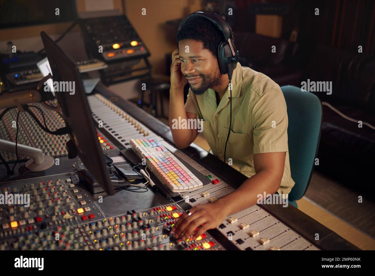 Computer, music and male producer in studio working on a album, song or audio with tech equipment. Happy, smile and black man radio presenter playing Stock Photo