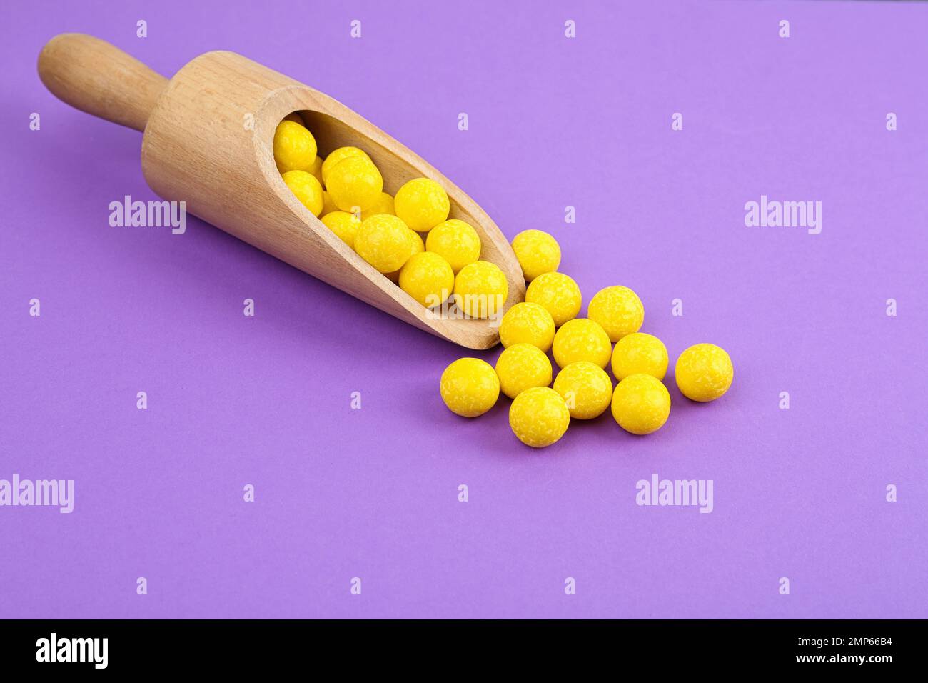 Delicious lemon chewing gums and scoop on purple background Stock Photo