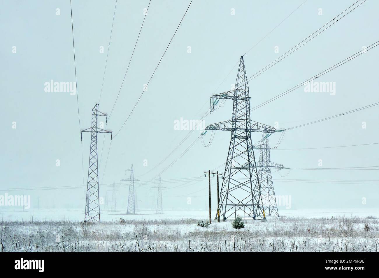 power line for industrial power transmission passing through the field electricity wires megawatts metal tower construction Stock Photo