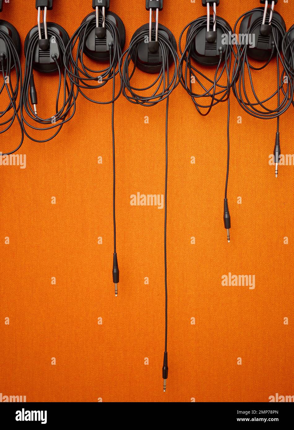Audio, cables and mockup on an orange wall background in a music studio for recording or sound engineering. Media, equipment and hanging wires in an Stock Photo